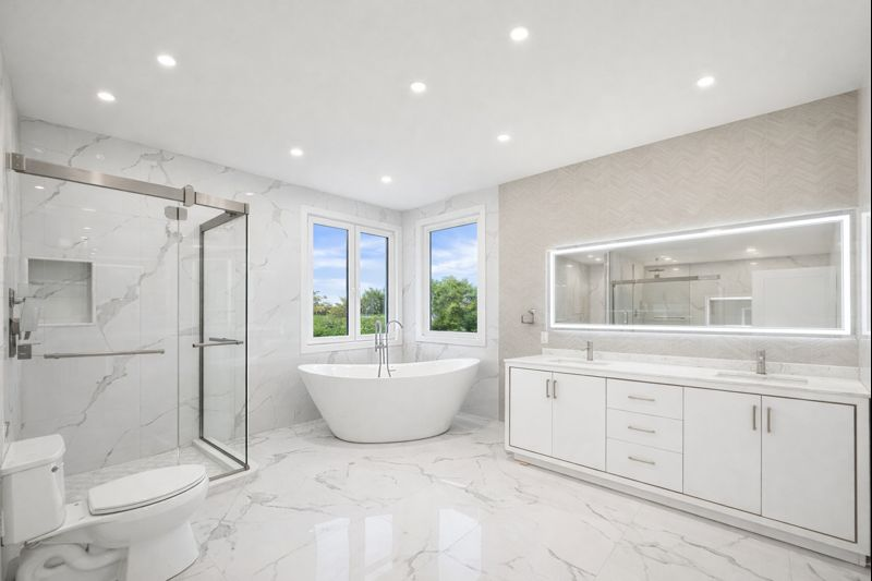 Bright white modern bathroom with freestanding tub, glass shower, and double vanity