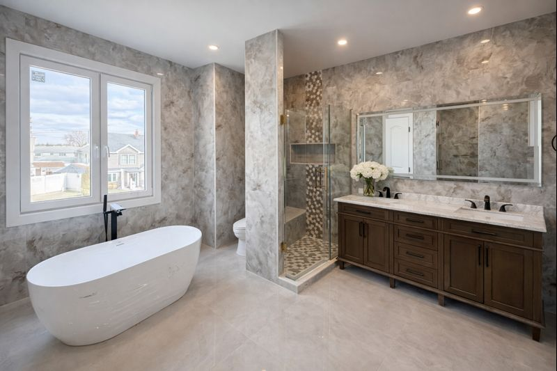 Spacious modern bathroom with freestanding tub, walk-in shower, double vanity, and marble-look tile walls.