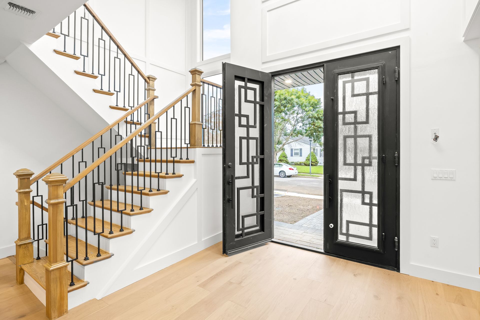 Bright entryway with staircase and open double doors leading outside