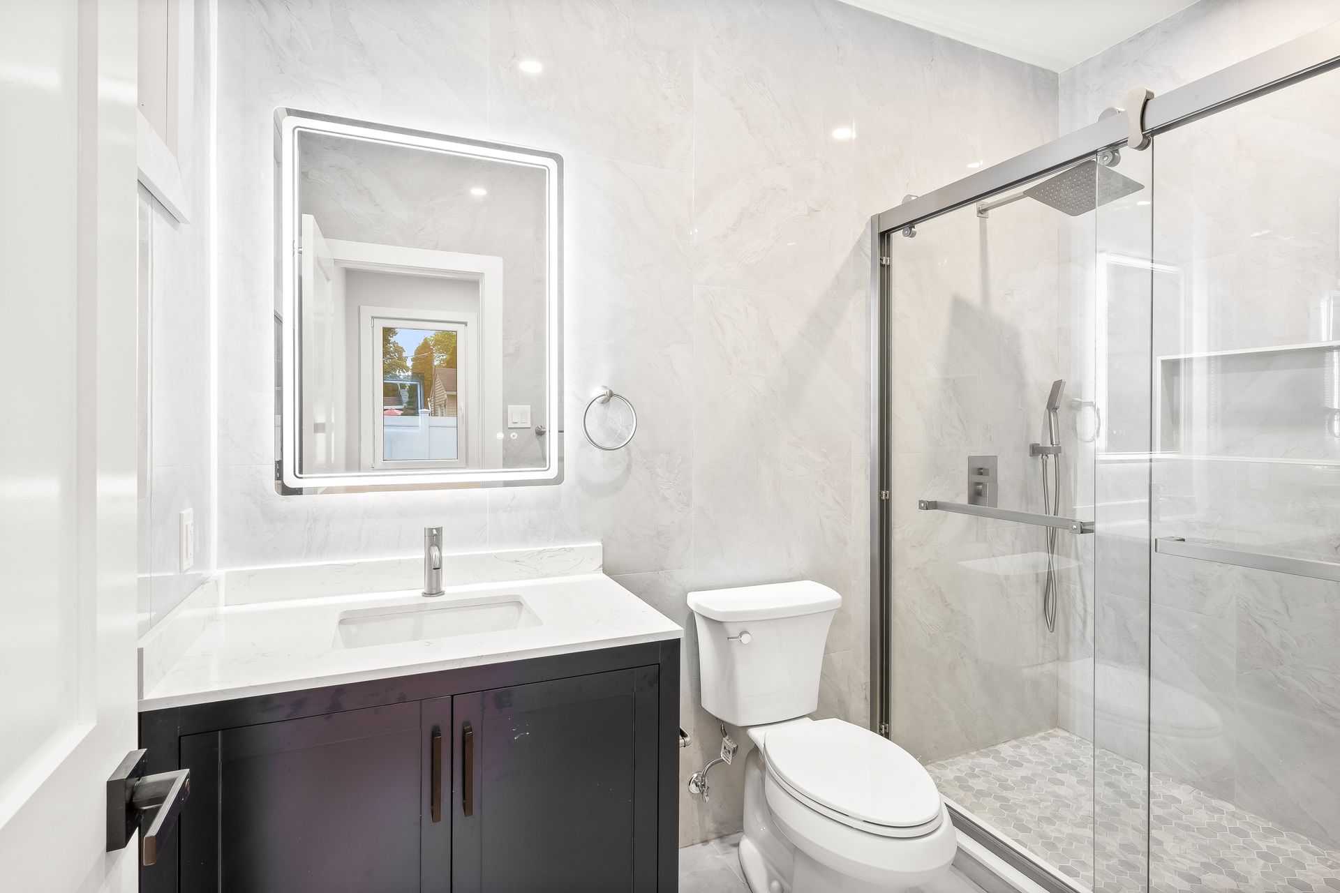 Modern white bathroom with vanity, mirror, toilet, and glass shower enclosure