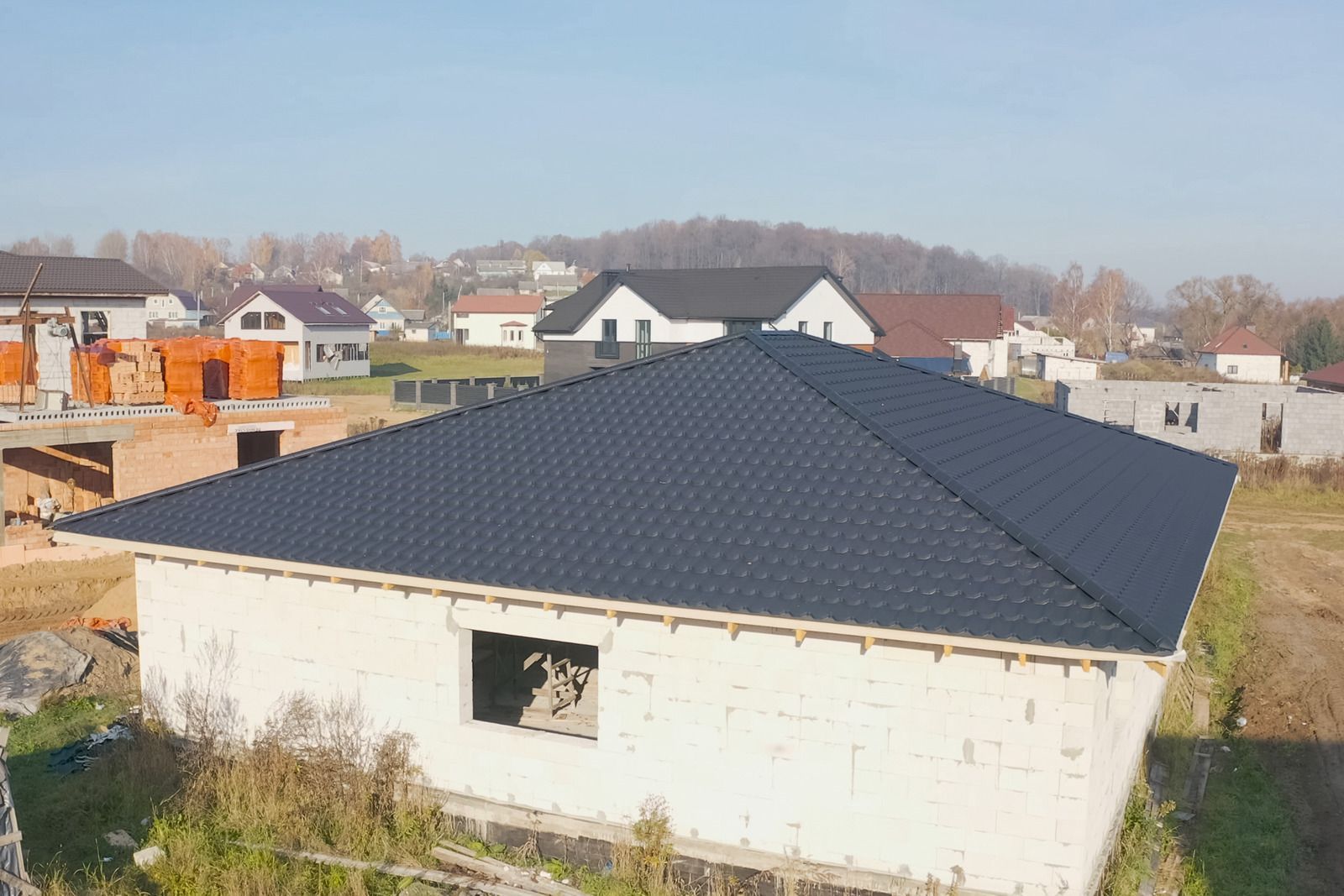Large house with a dark gray hip roof in a suburban neighborhood.