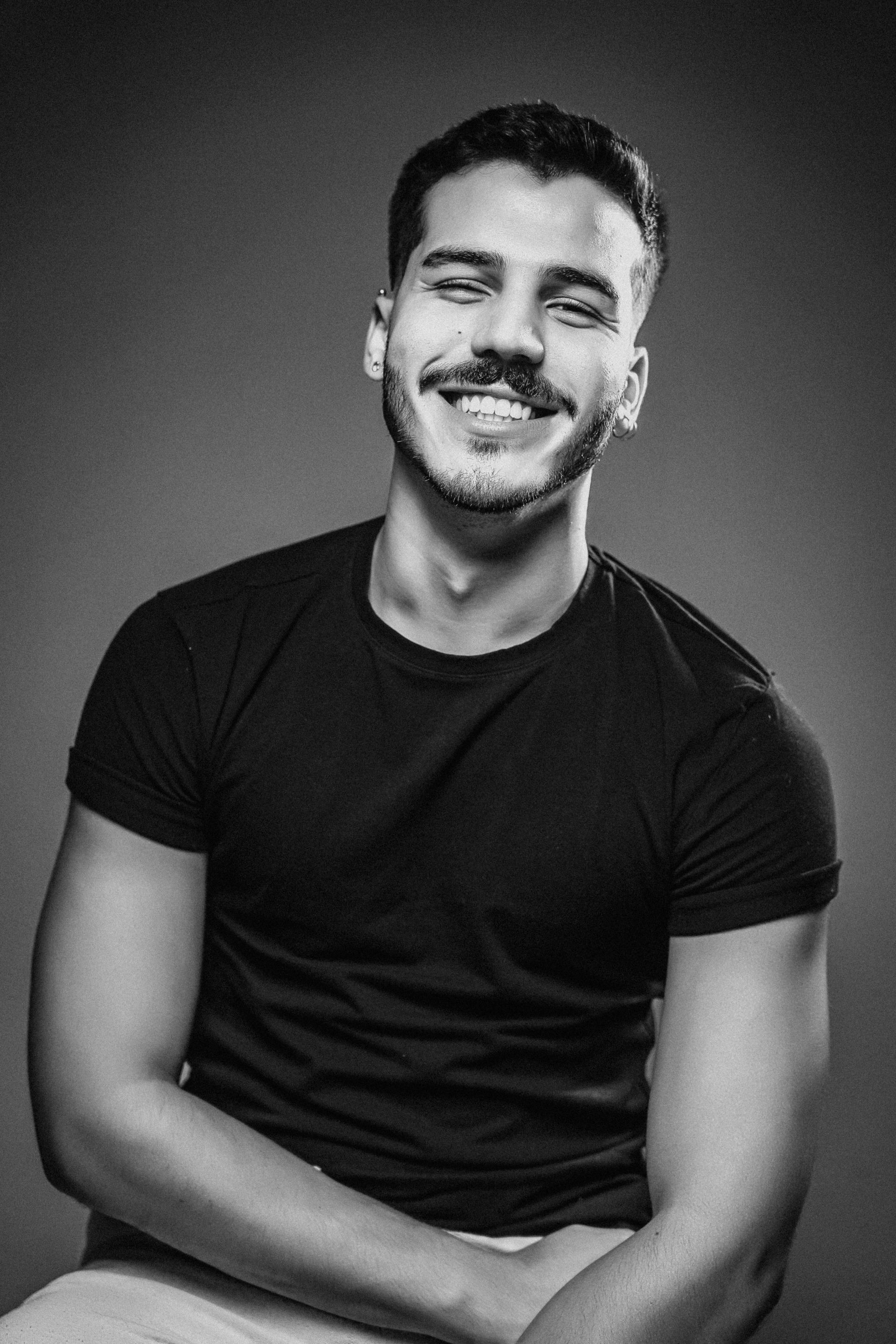 Retrato em preto e branco de uma pessoa sorridente vestindo uma camiseta escura.