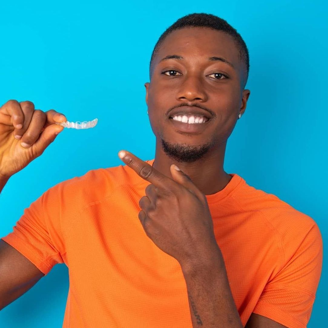 young African American man holding clear aligners