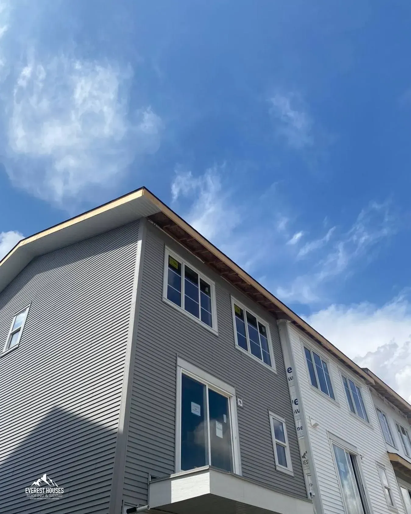 Modern gray townhouse exterior with white trim against a blue sky