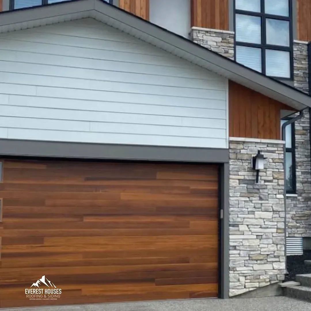 Modern house exterior with a wood garage door, stone siding, and gray siding above
