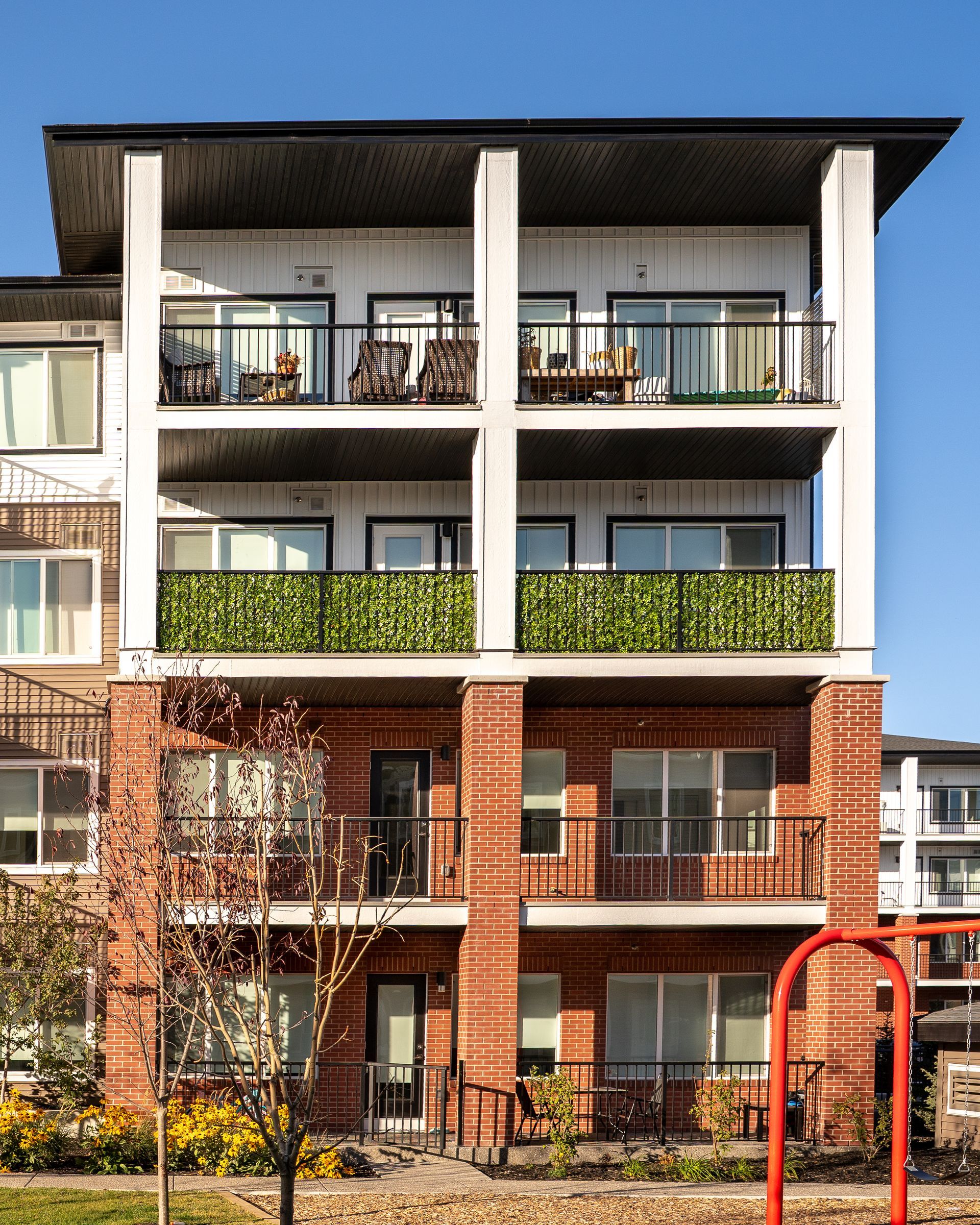 Modern brick and white apartment building with balconies and a red bench in front Modern brick and white apartment building with balconies and a red bench in front