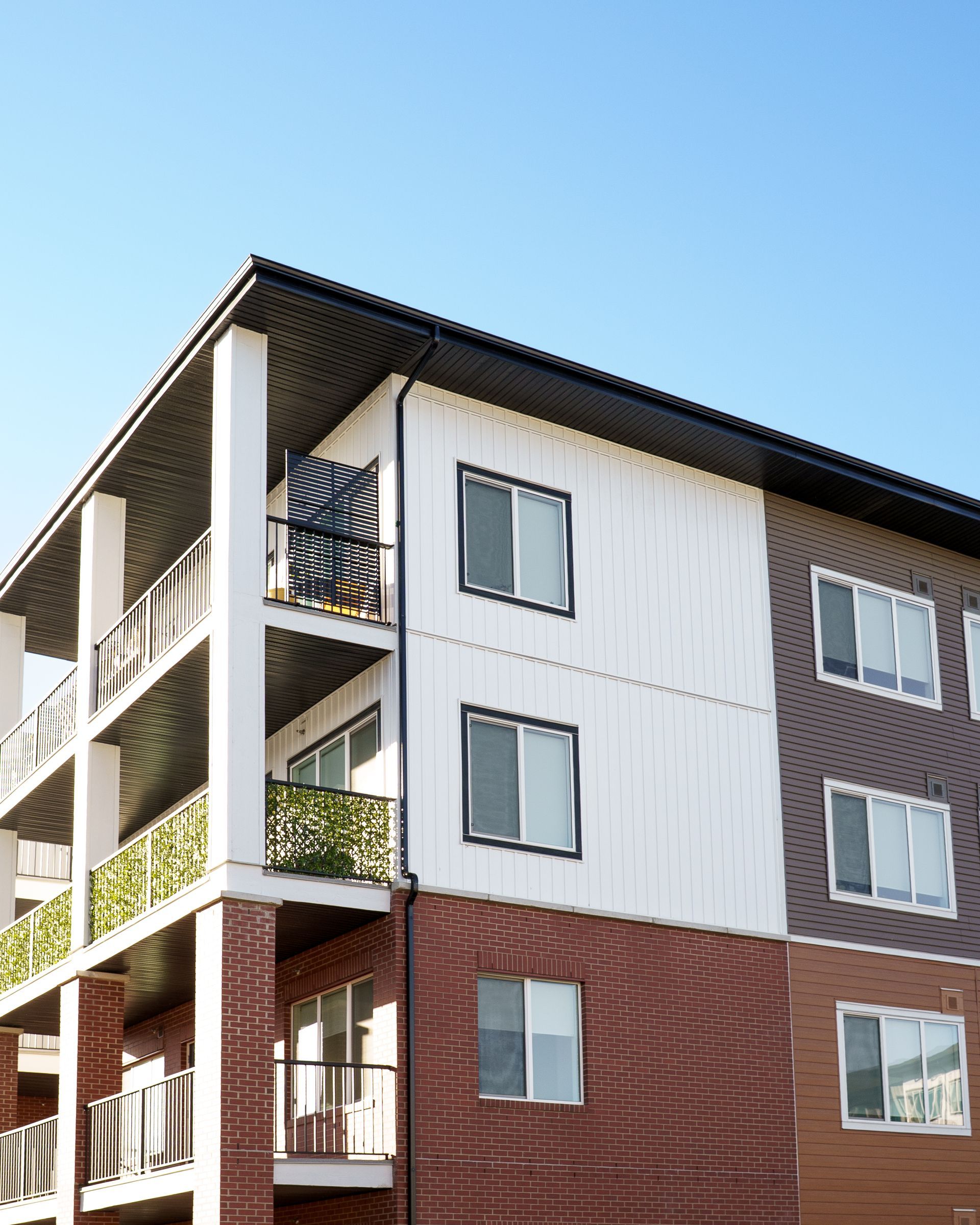 Modern apartment building with white and brick exterior against a blue sky Modern apartment building with white and brick exterior against a blue sky