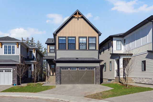 Front view of a beige two-story house with a double garage in a suburban neighborhood