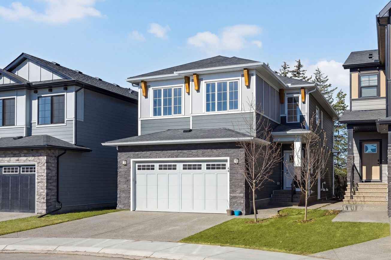 New two-story suburban house with stone and brick facade, white garage door, and a small front lawn