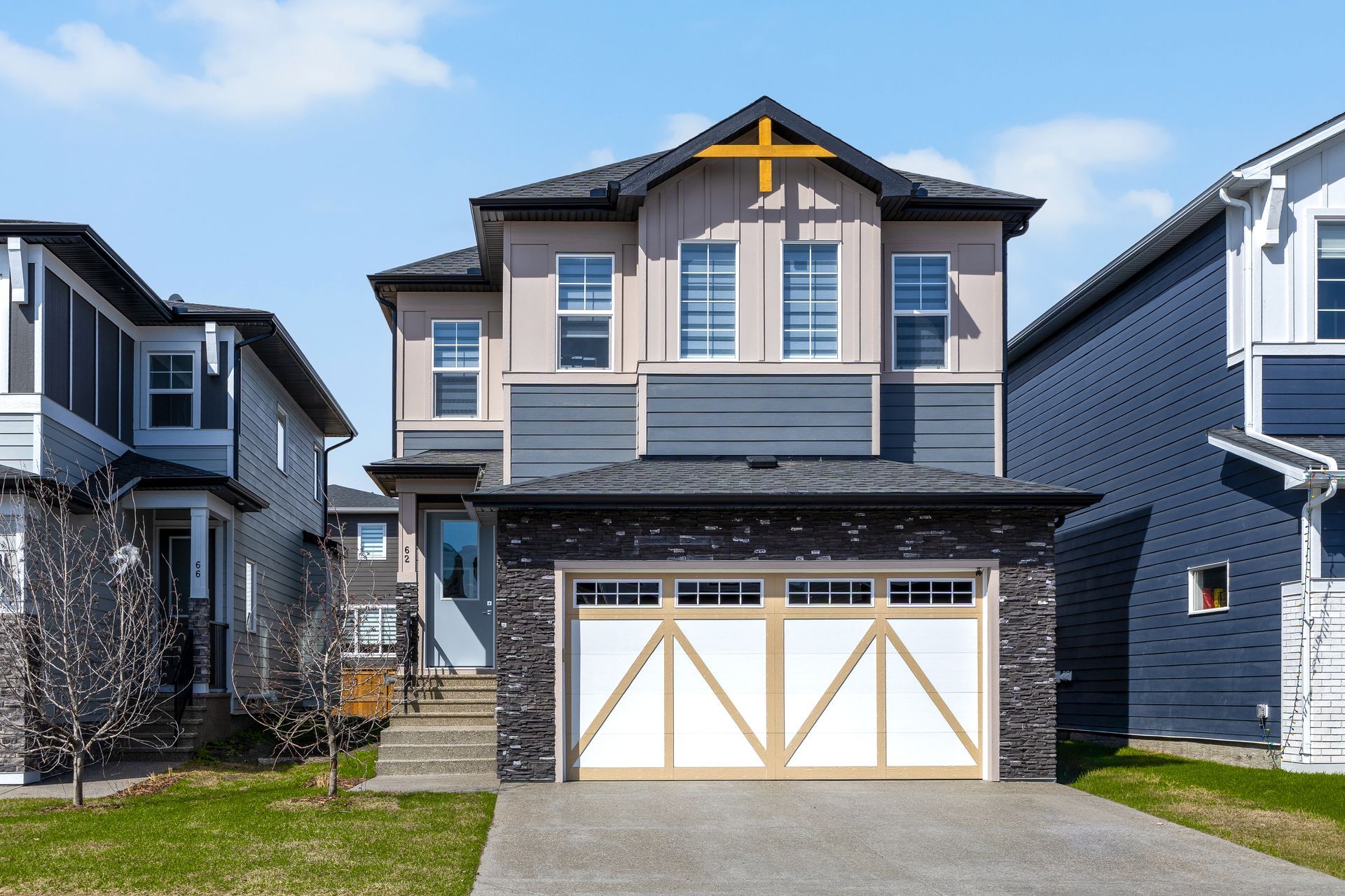 Suburban two-story house with beige siding, dark trim, and double garage doors Suburban two-story house with beige siding, dark trim, and double garage doors