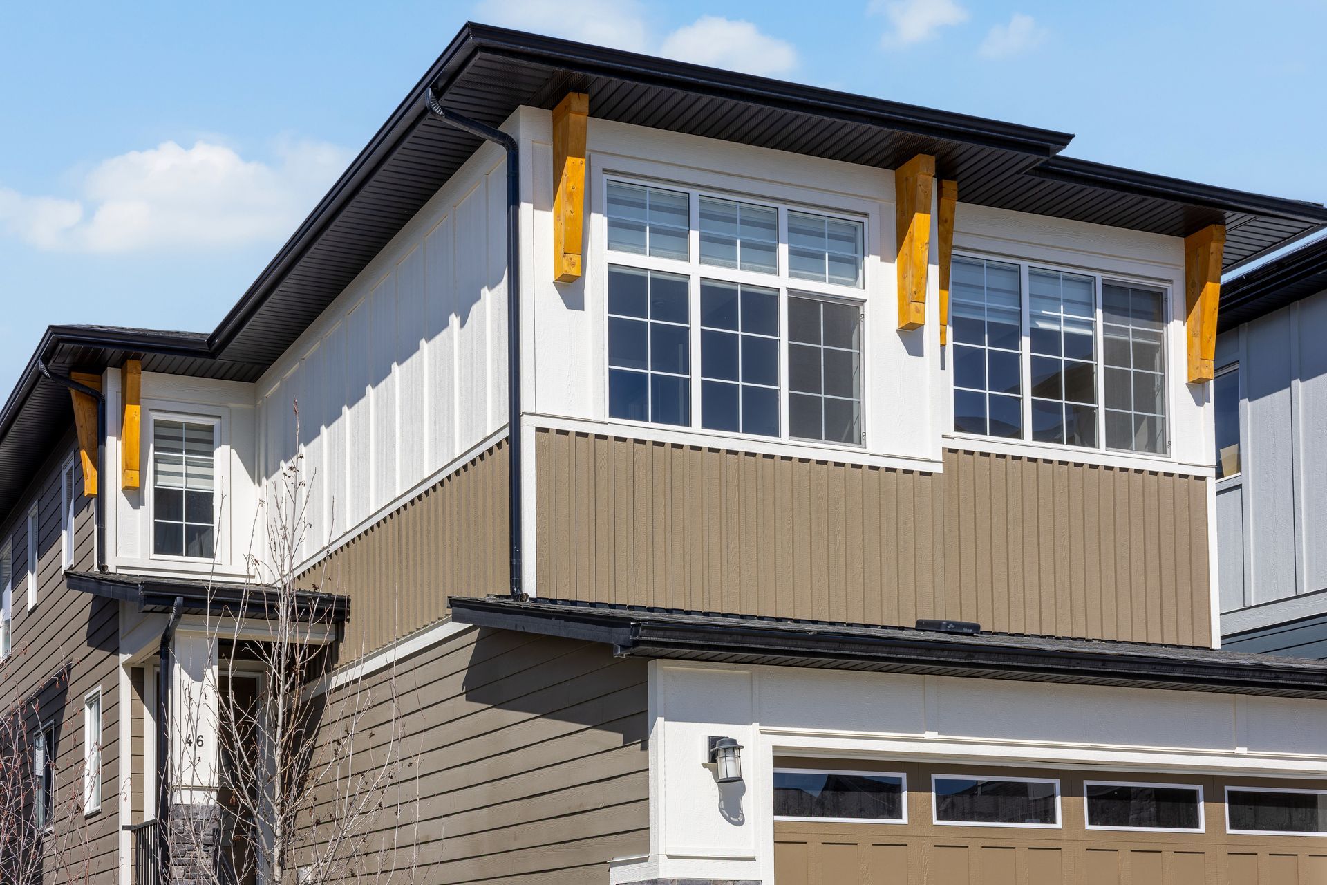 Modern two-story house exterior with gray siding, white trim, and a garage under a blue sky Modern two-story house exterior with gray siding, white trim, and a garage under a blue sky