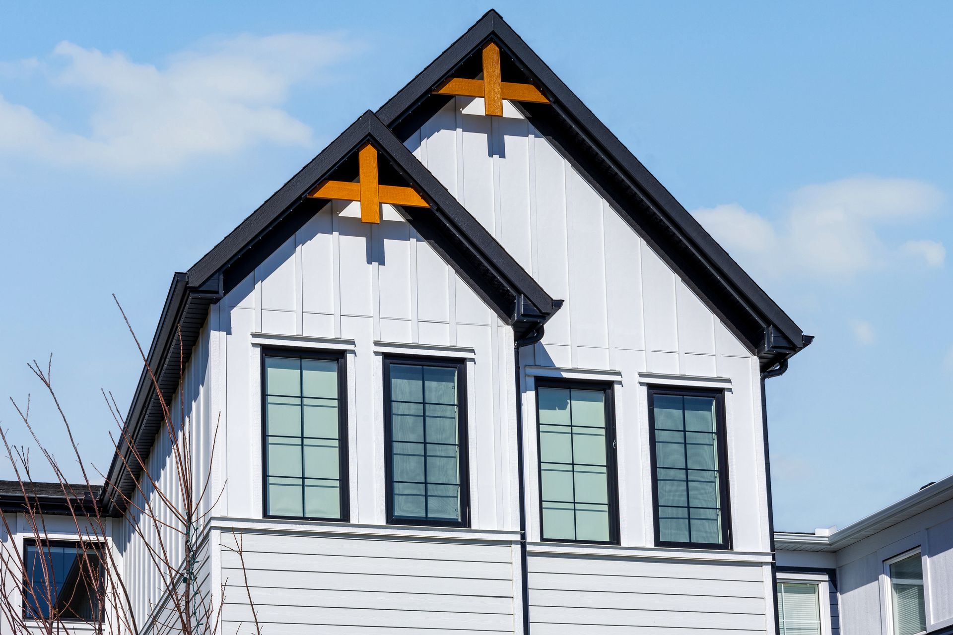 White building facade with black gabled roofs and orange cross accents against a blue sky White building facade with black gabled roofs and orange cross accents against a blue sky