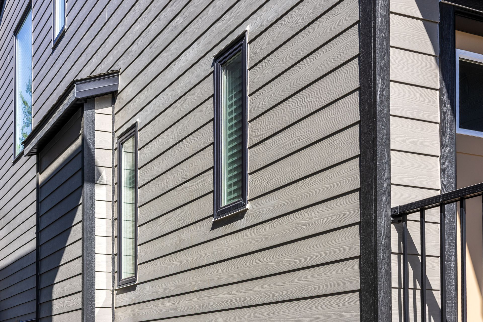 Gray house siding with narrow vertical windows and a balcony railing on the right Gray house siding with narrow vertical windows and a balcony railing on the right