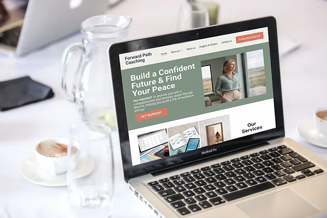 Laptop displaying a financial website on a white desk beside a glass, cup, and notebook.