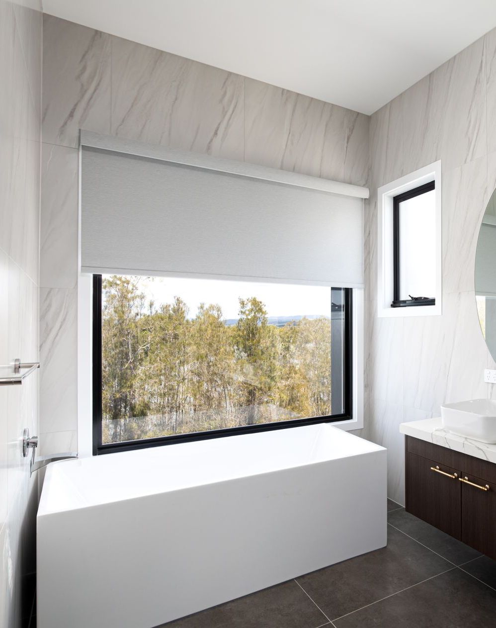 A bathroom with a bathtub , sink , mirror and window.