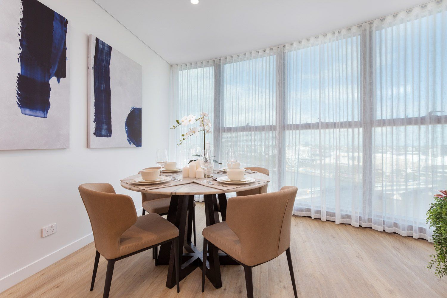 A dining room with a table and chairs and a large window.