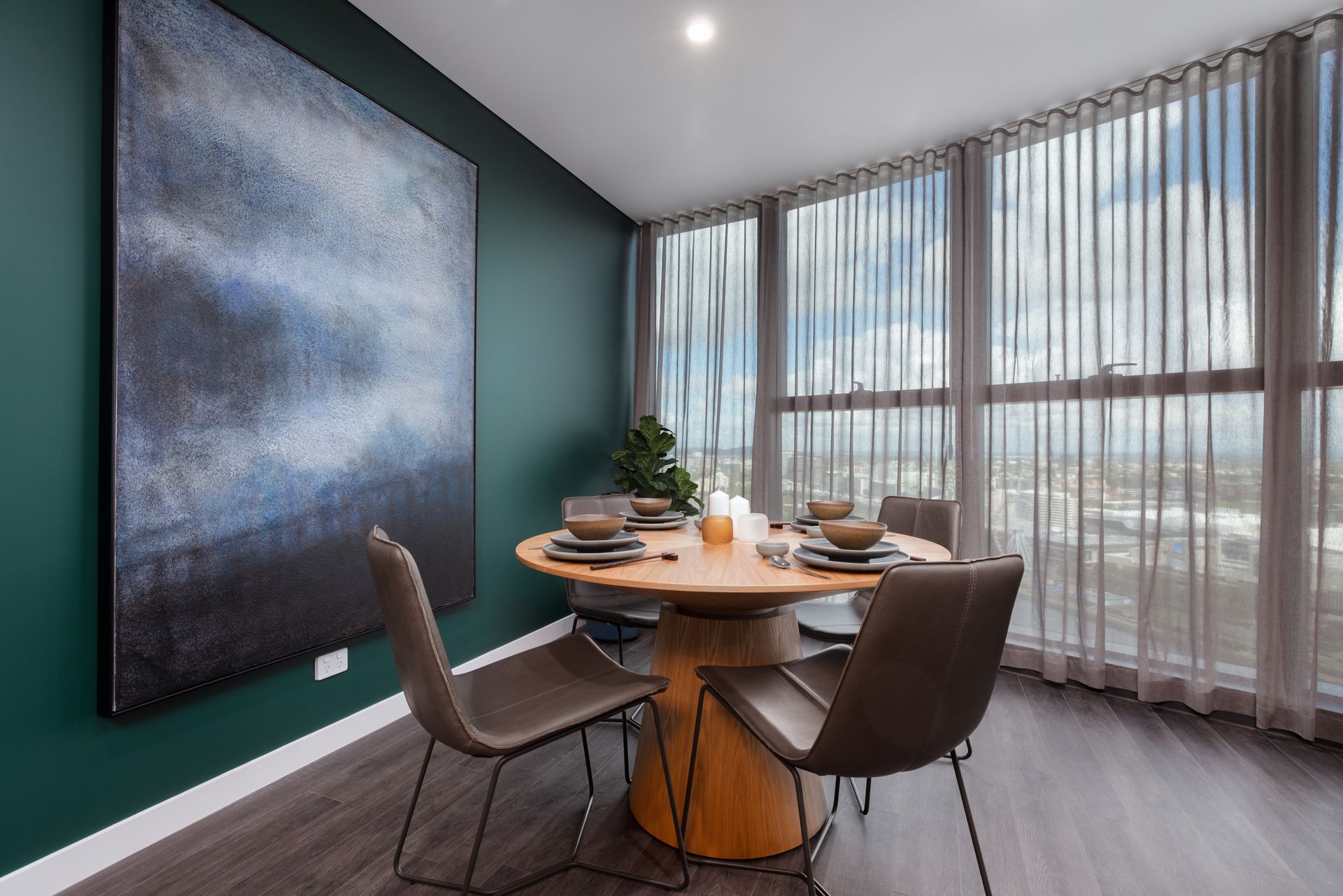 A dining room with a table and chairs and a large painting on the wall.