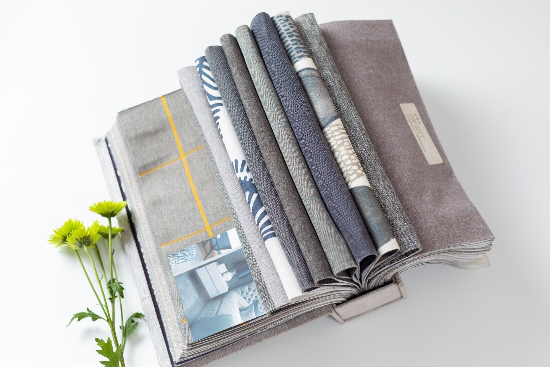 A stack of fabrics is sitting on top of a book next to a flower.