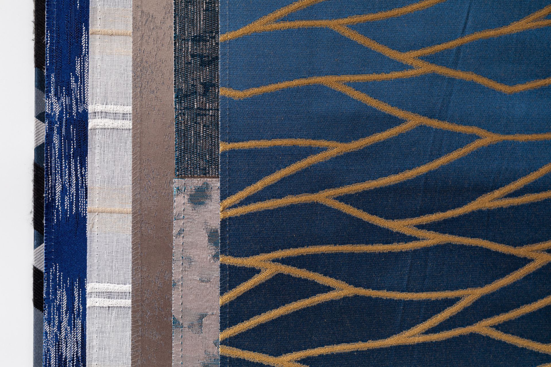 A close up of a blue and gold rug on a white surface.