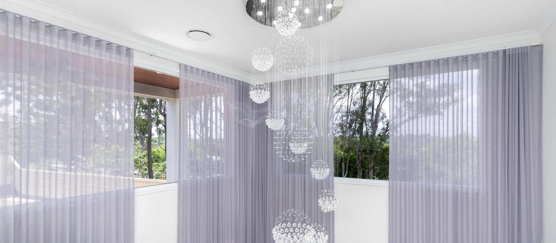 A living room with purple curtains and a chandelier hanging from the ceiling.
