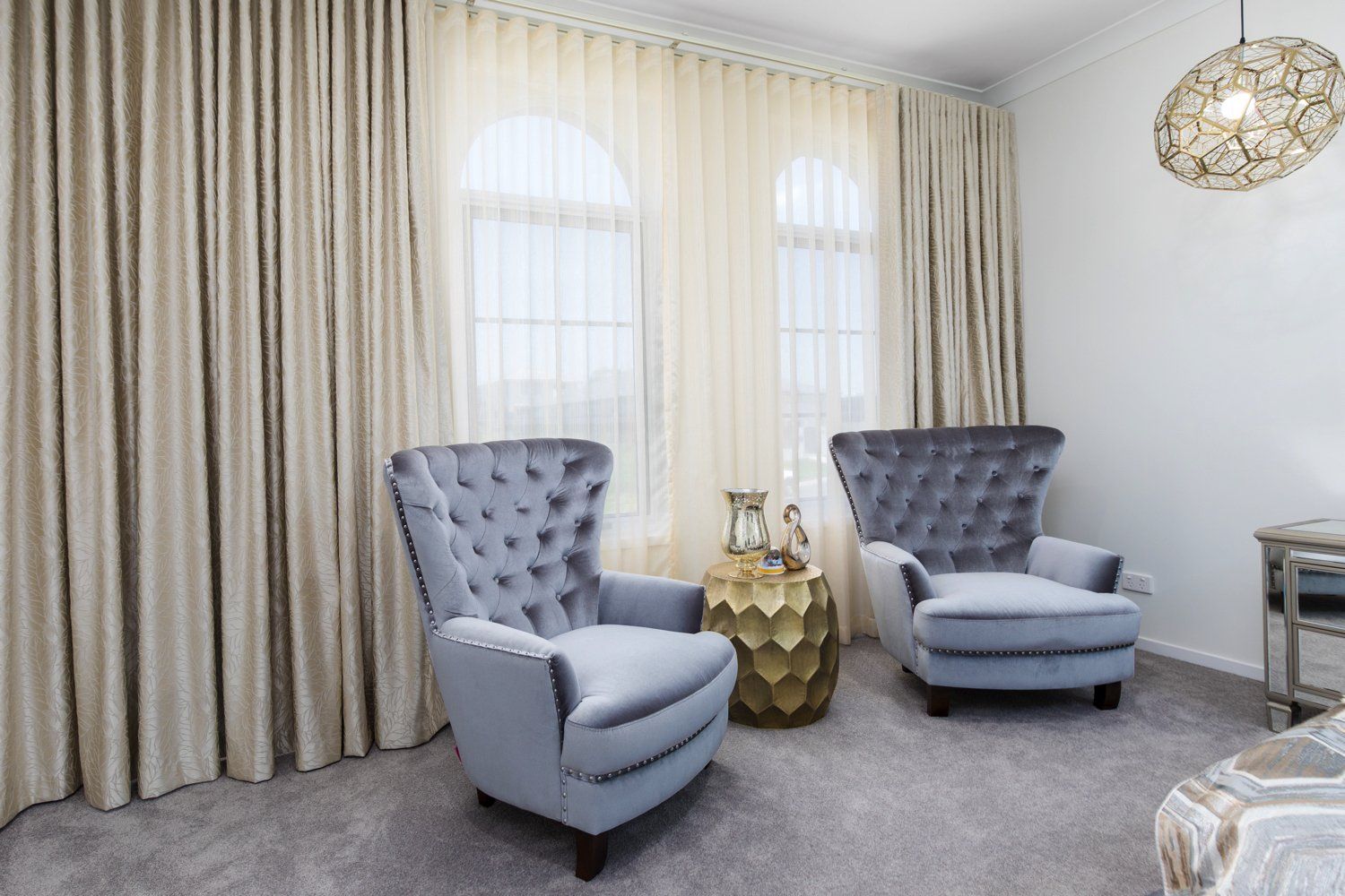 A living room with two chairs and a table in front of a window.