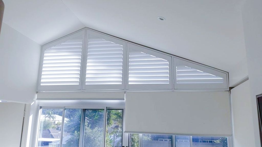 A living room with a large window and shutters on it.