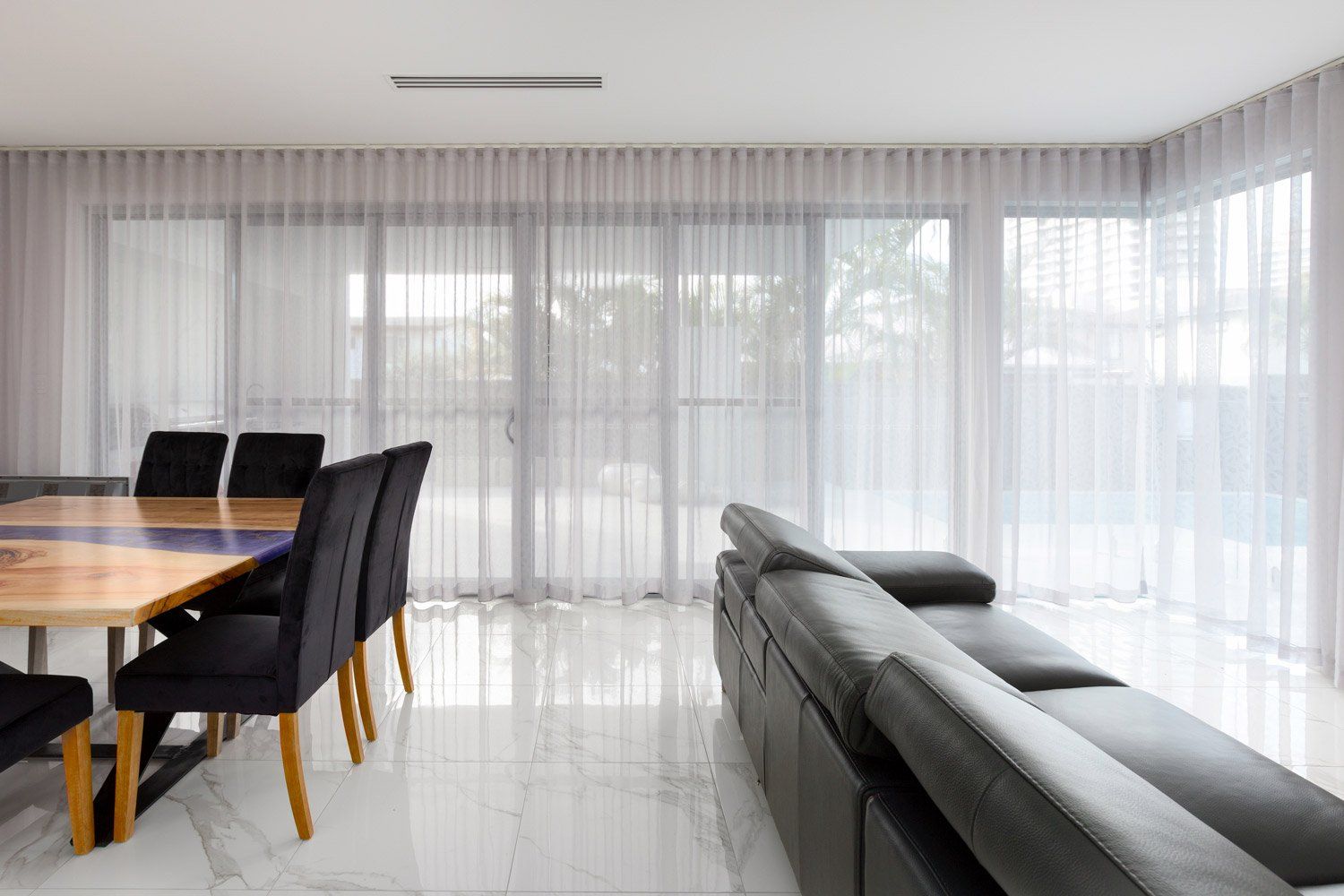 A living room with a couch , table , chairs and curtains.