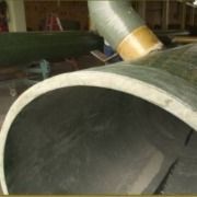 A close up of a curved metal pipe in a factory.