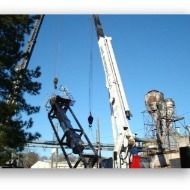 A large crane is lifting a large object in a factory.