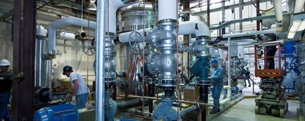A group of people are working on pipes in a factory.