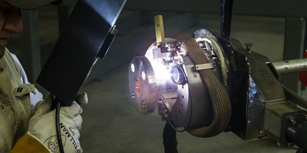 A man is welding a piece of metal in a factory.