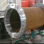 A large metal pipe is sitting on top of a table in a factory.