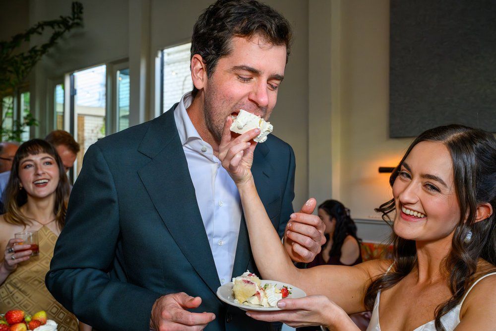 People at a party sharing cake, smiling in a bright indoor setting