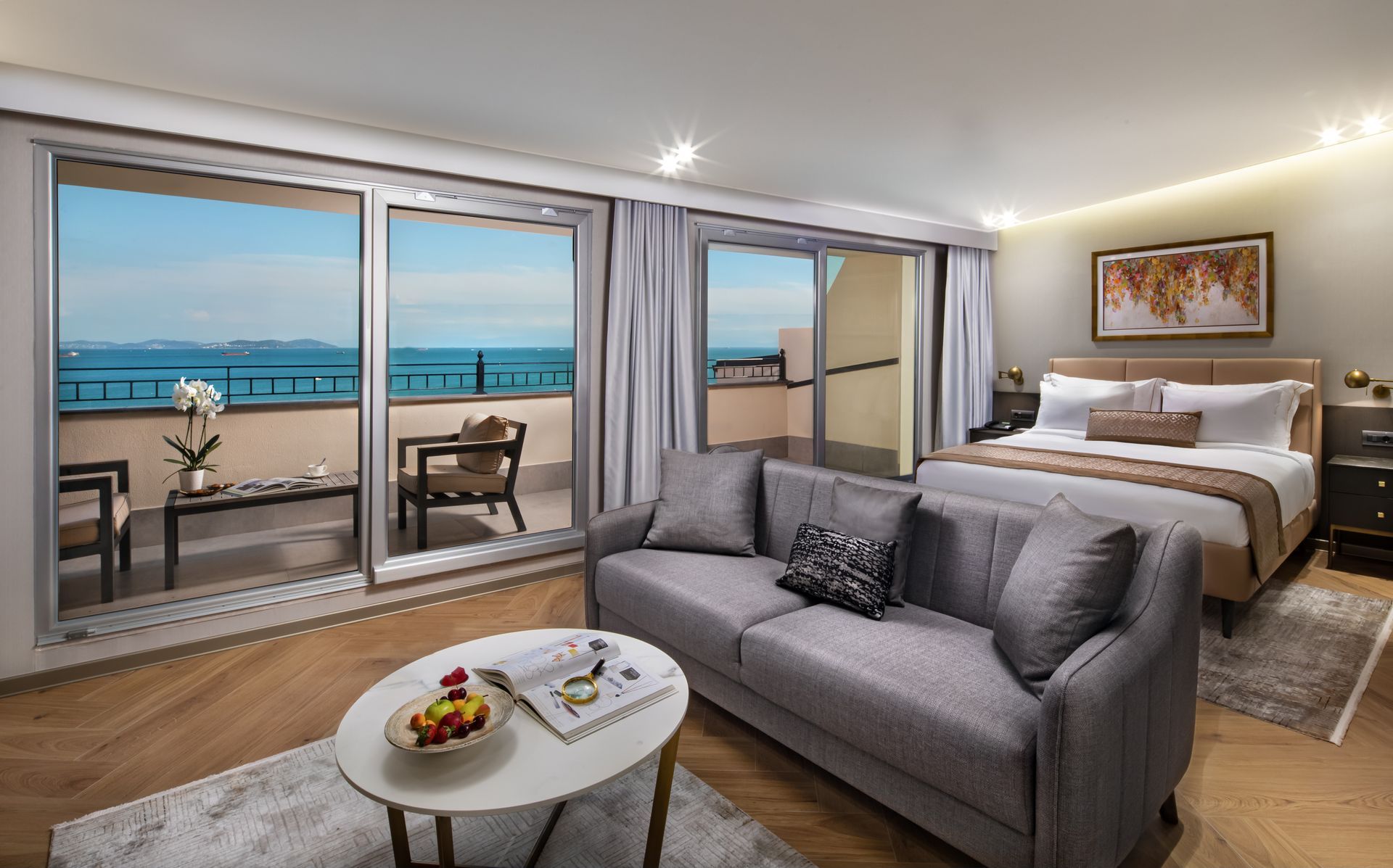Modern beachfront hotel suite with gray sofa, bed, and balcony ocean view