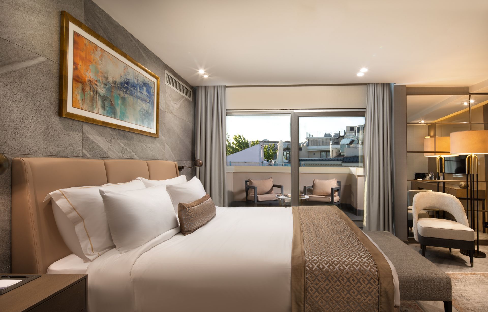 Modern hotel room with a king bed, balcony view, and seating area