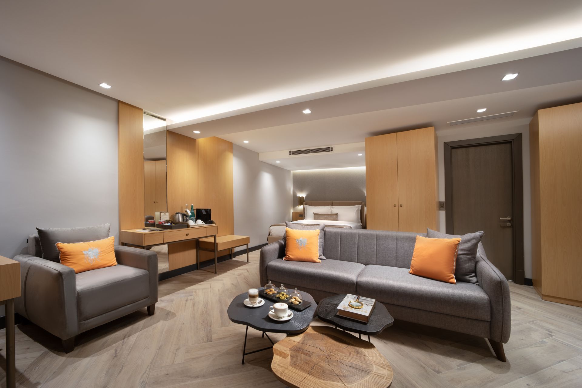 Modern living room with gray sofas, orange cushions, wood accents, and a coffee table
