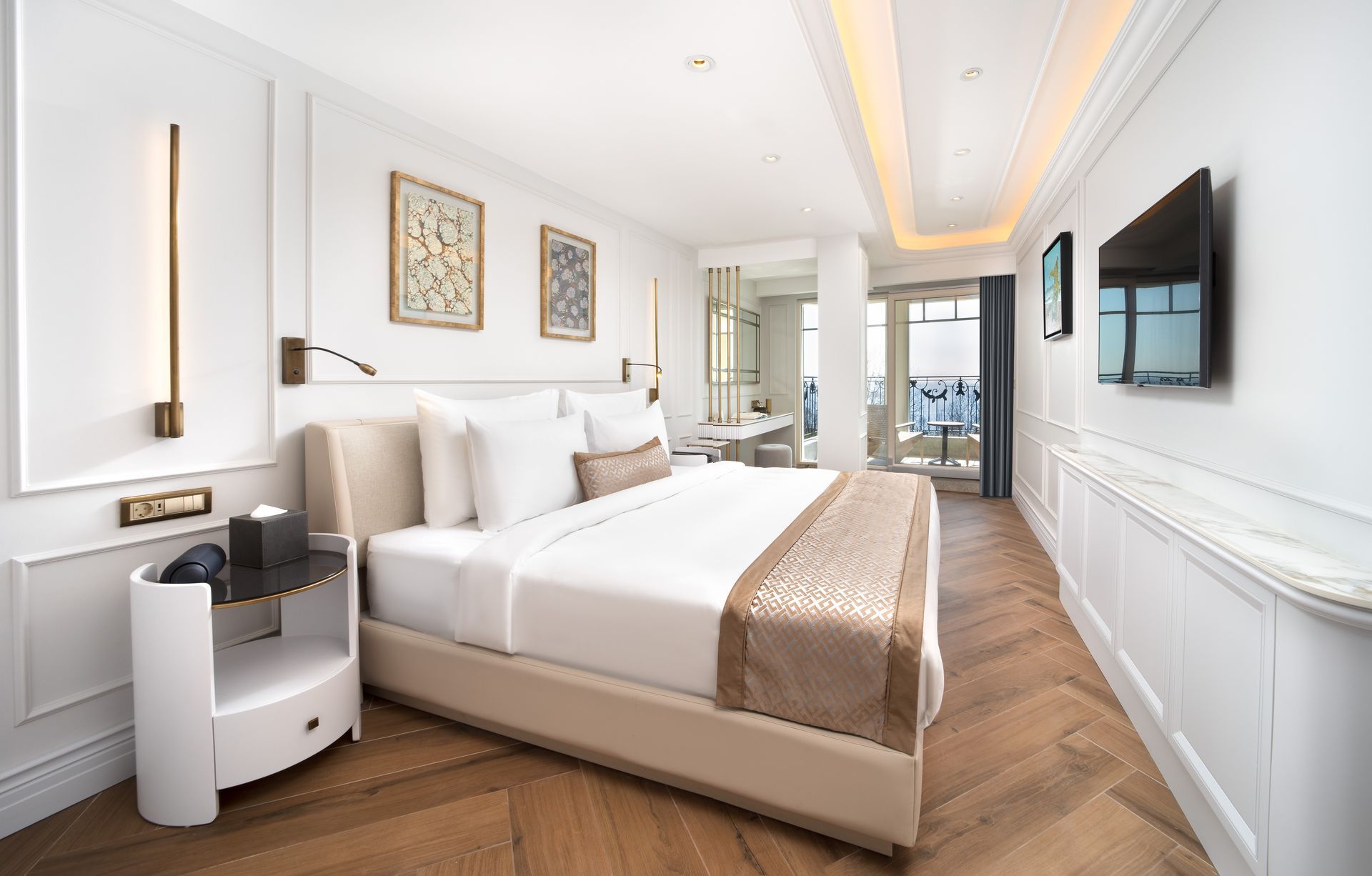 Bright modern bedroom with white bed, wood floor, wall art, and a TV on the right.