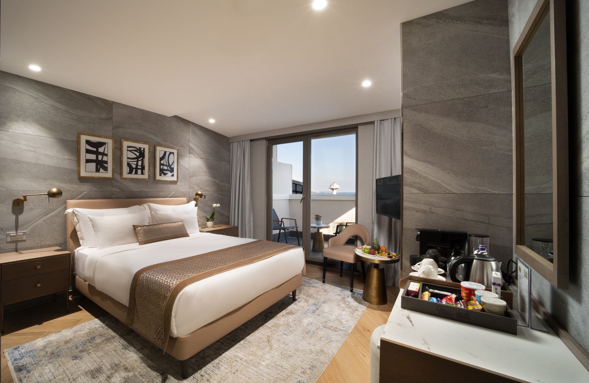 Modern hotel room with a large bed, gray walls, and a balcony view.
