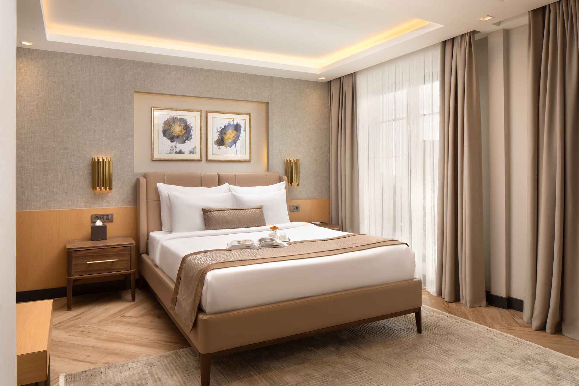 Elegant beige bedroom with a bed, nightstands, wall art, and sheer curtains by a large window