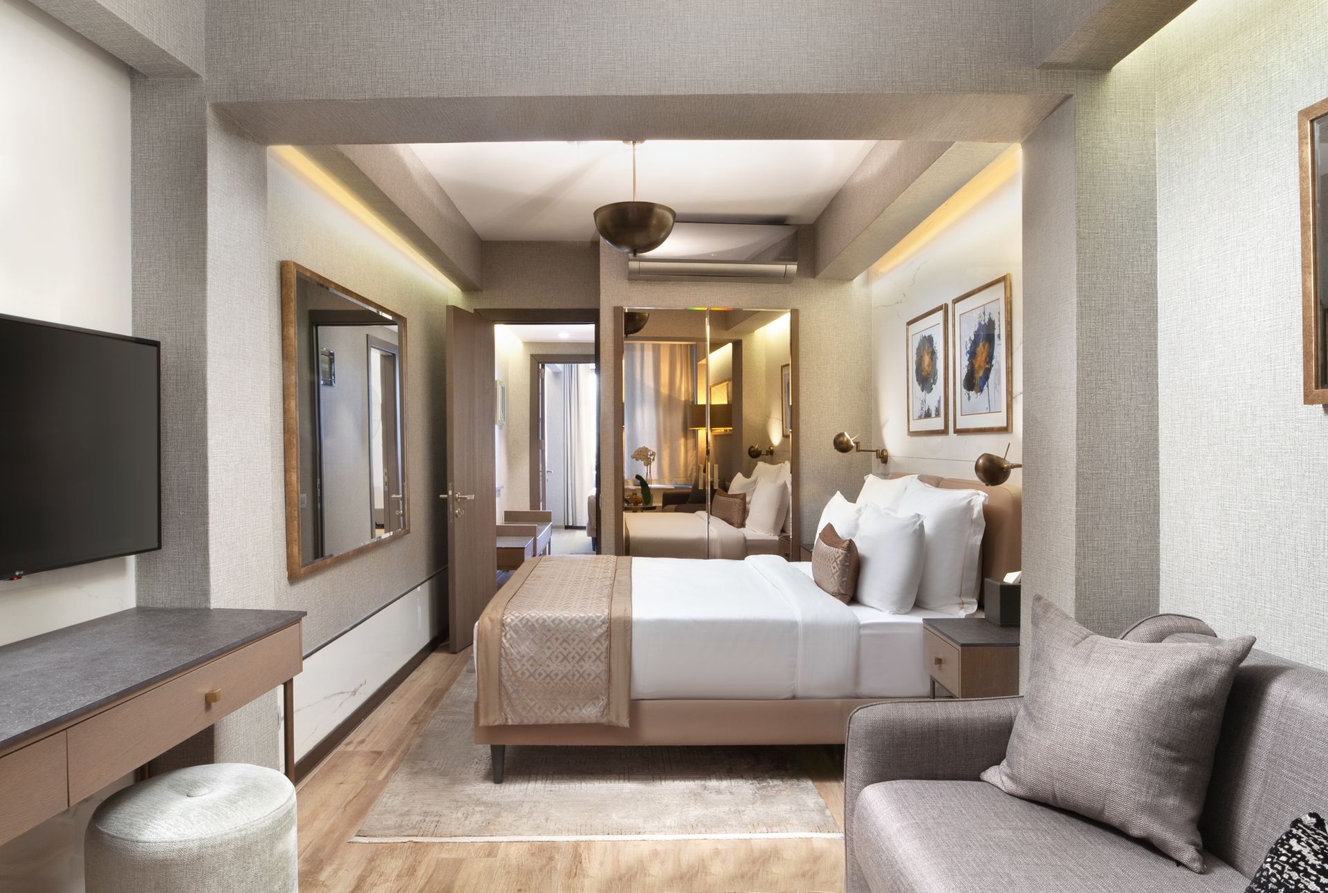 Modern hotel room with a bed, sofa, desk, and warm ambient lighting