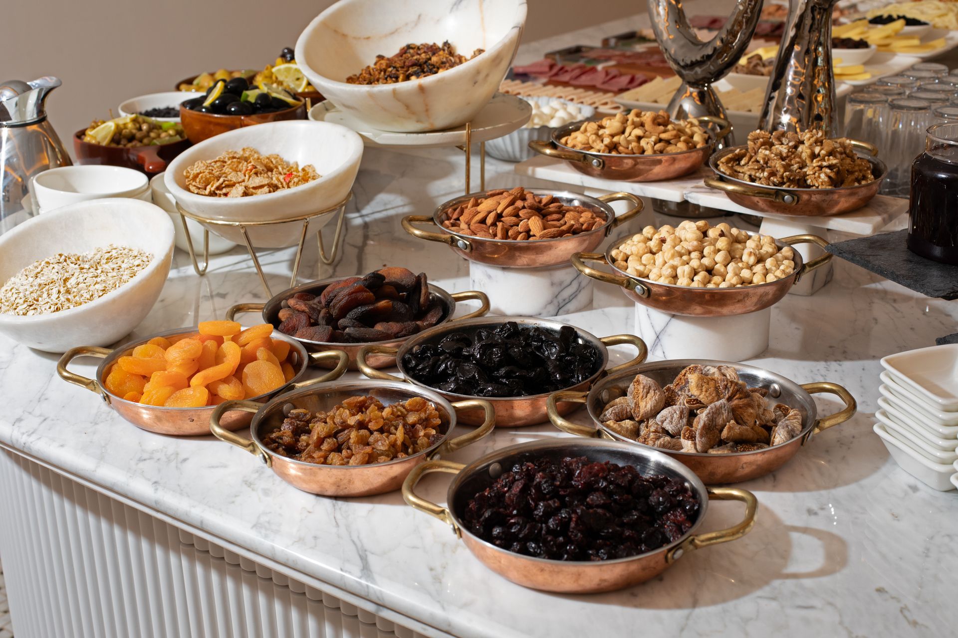 Buffet table with assorted bowls of nuts, dried fruits, and snacks on a white tablecloth