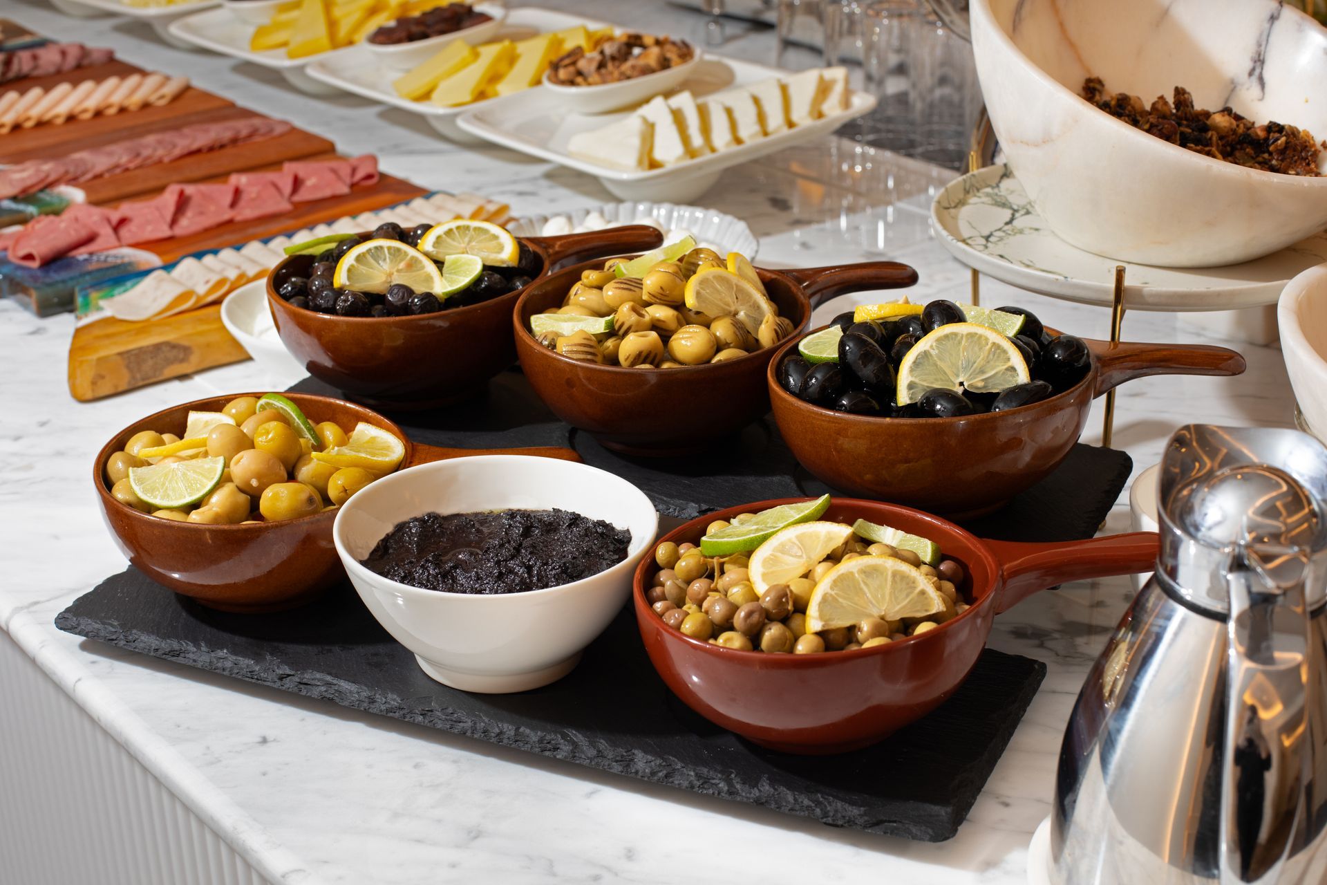 Assorted desserts in bowls on a buffet table, including fruit, yogurt, and granola toppings