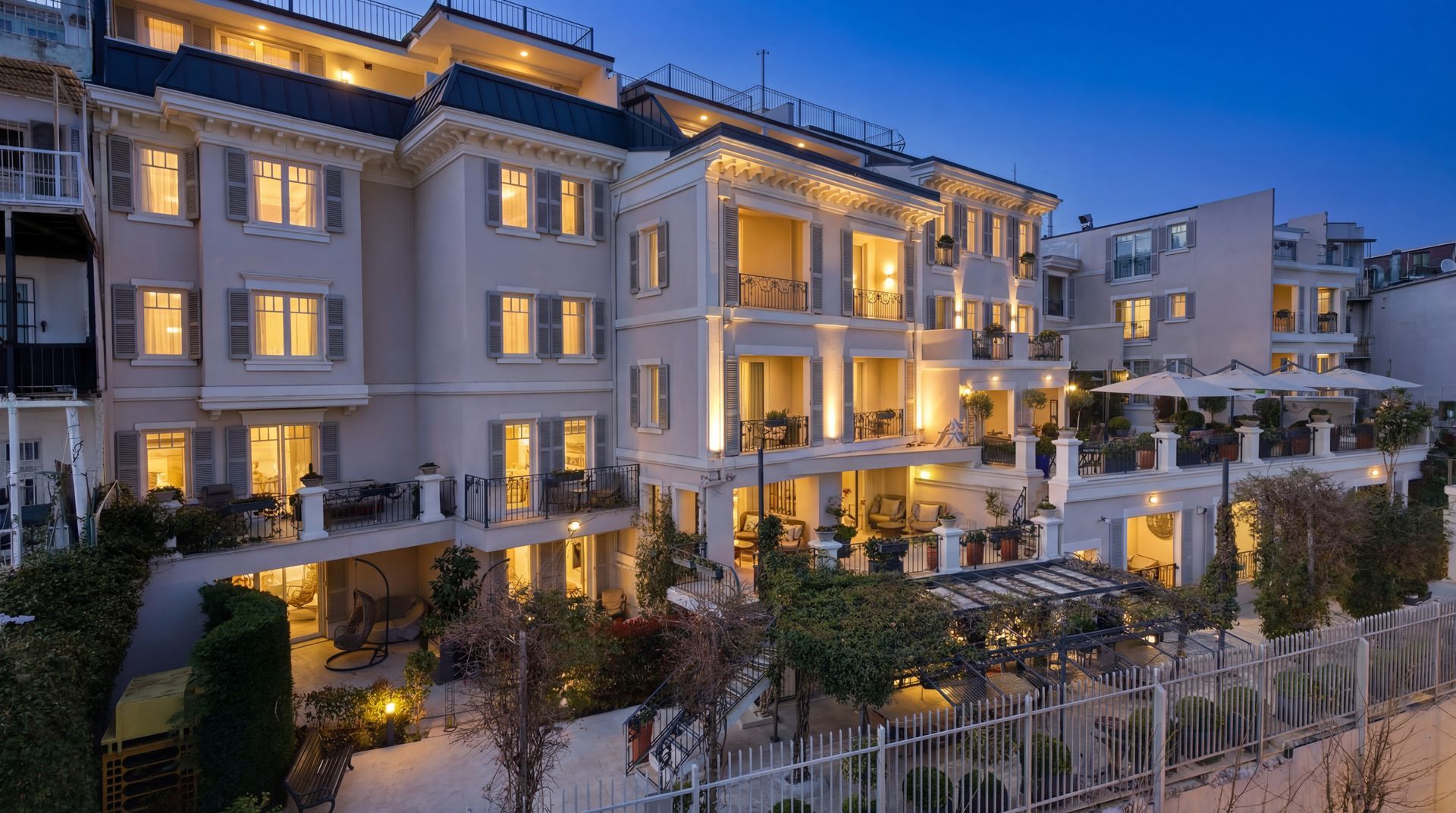 Luxury hotel building at dusk with warm lit balconies and landscaped garden in front