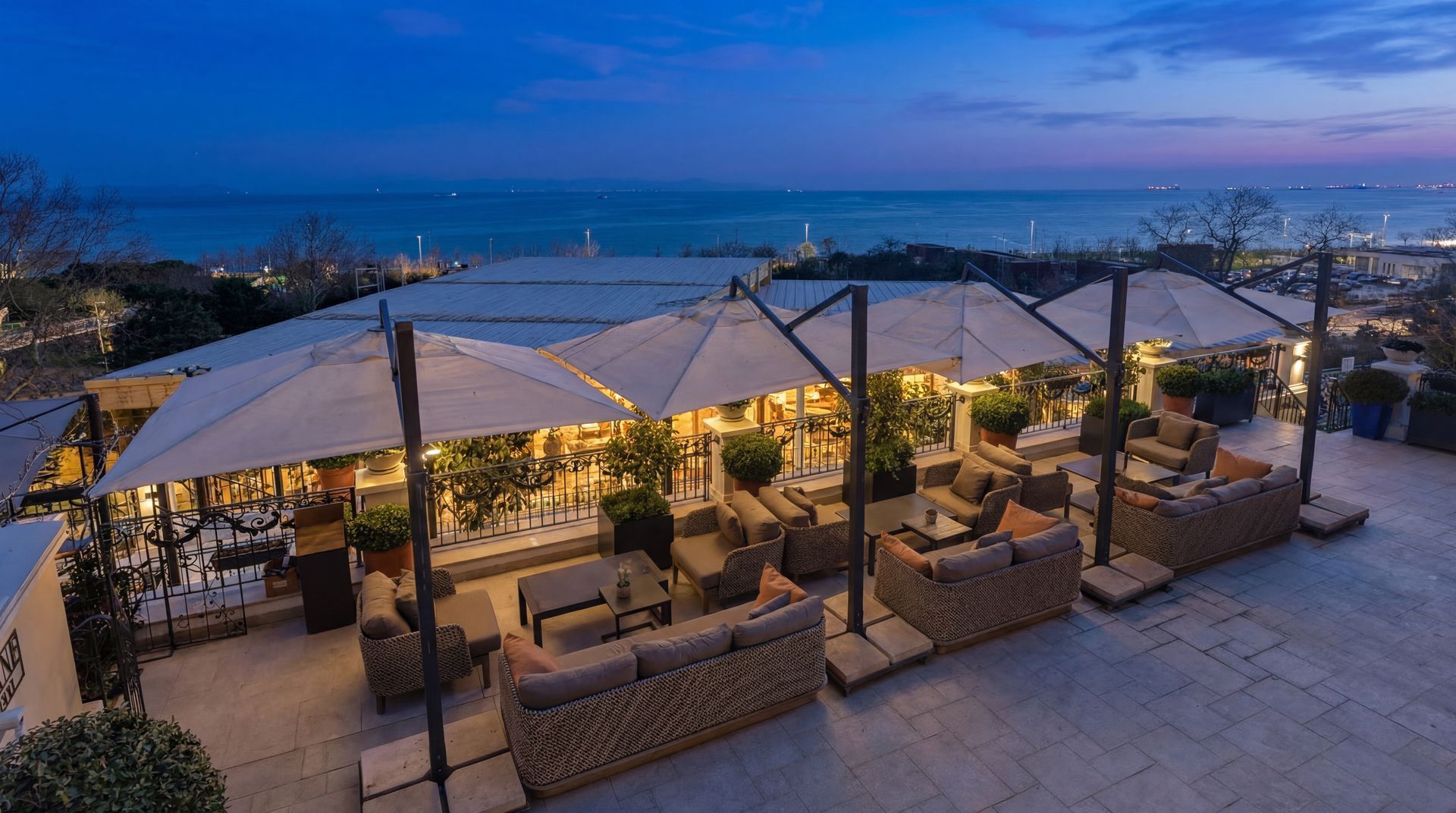 Outdoor rooftop lounge at dusk with white canopy seating and city lights in the background