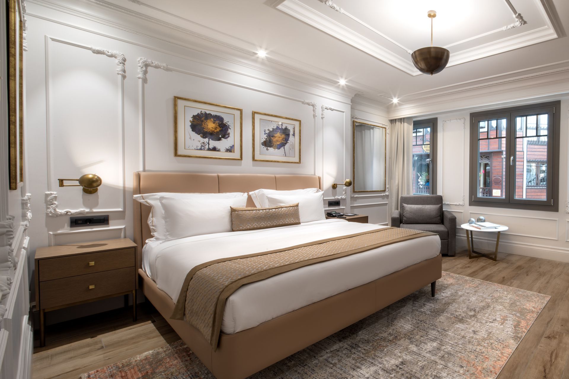 Elegant white bedroom with a large bed, framed artwork, and soft neutral decor.