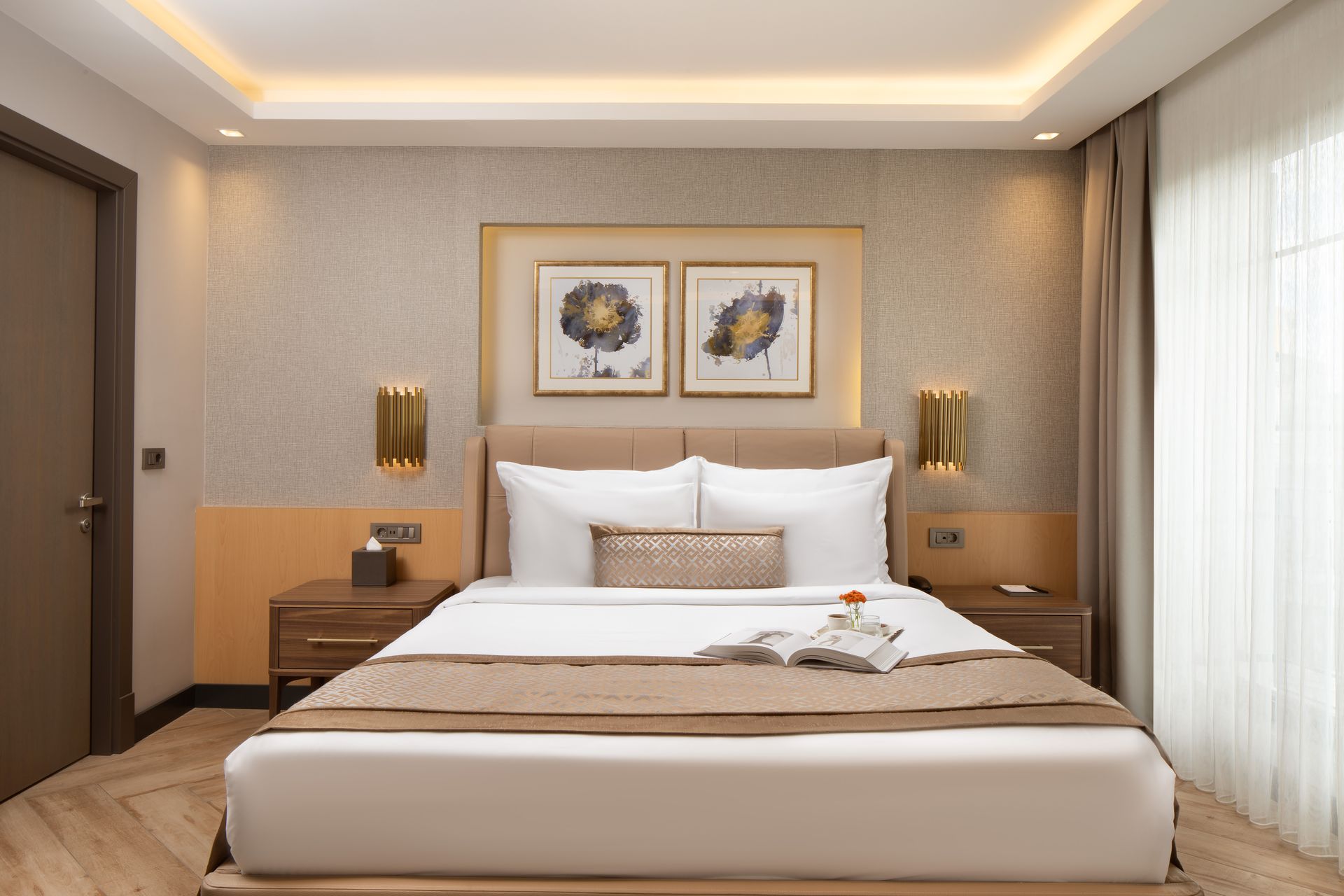 Modern bedroom with a king bed, warm wood accents, and framed floral art above the headboard