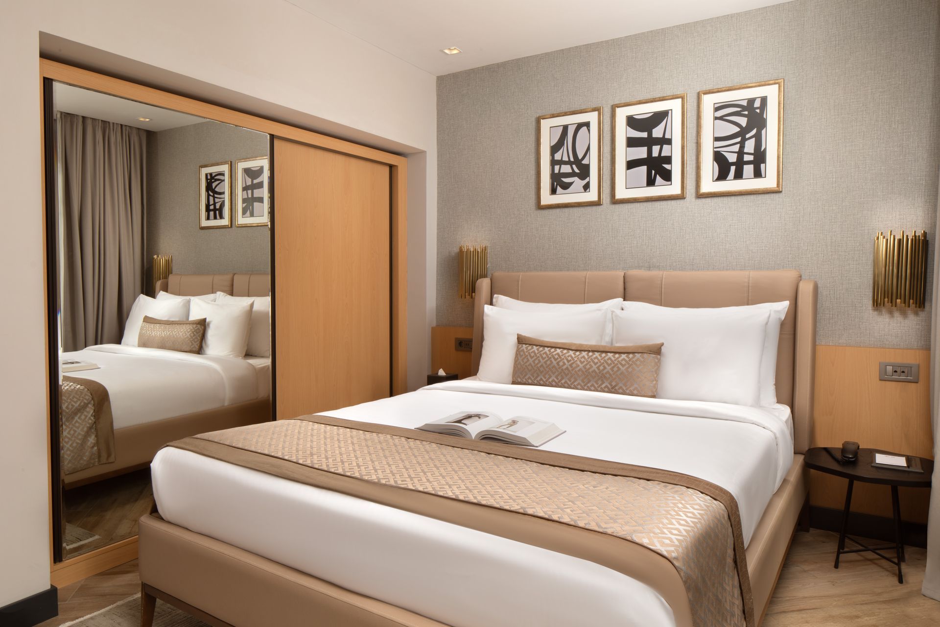 Modern bedroom with a large bed, mirrored wardrobe, beige decor, and framed wall art