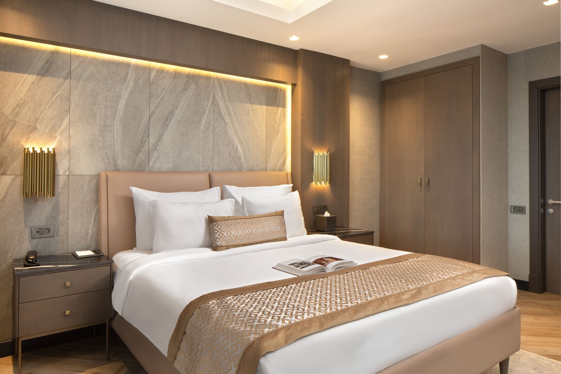 Modern hotel bedroom with a neatly made king bed, warm wood accents, and bedside lamps