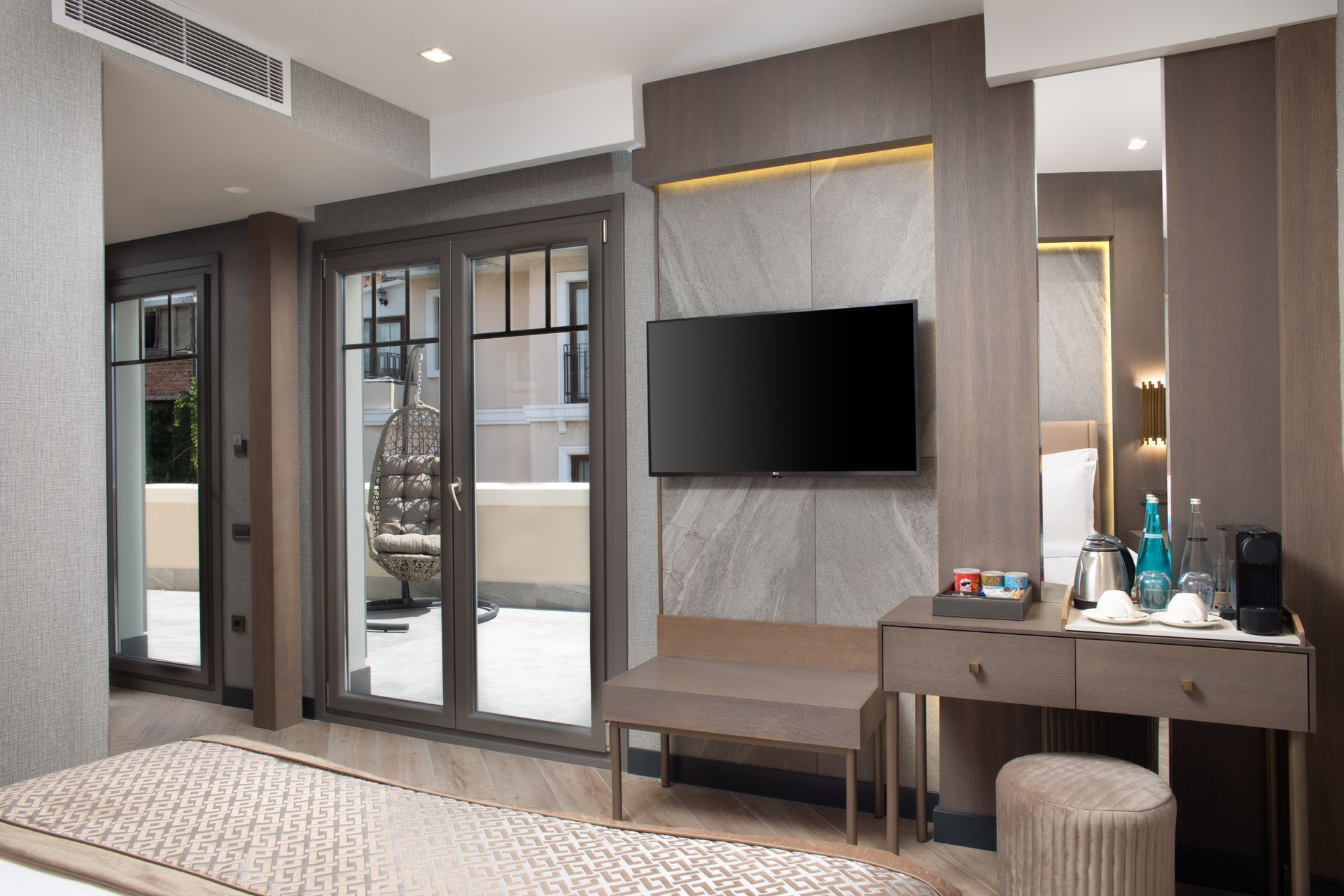 Modern hotel room interior with TV, sliding glass doors, and a vanity table