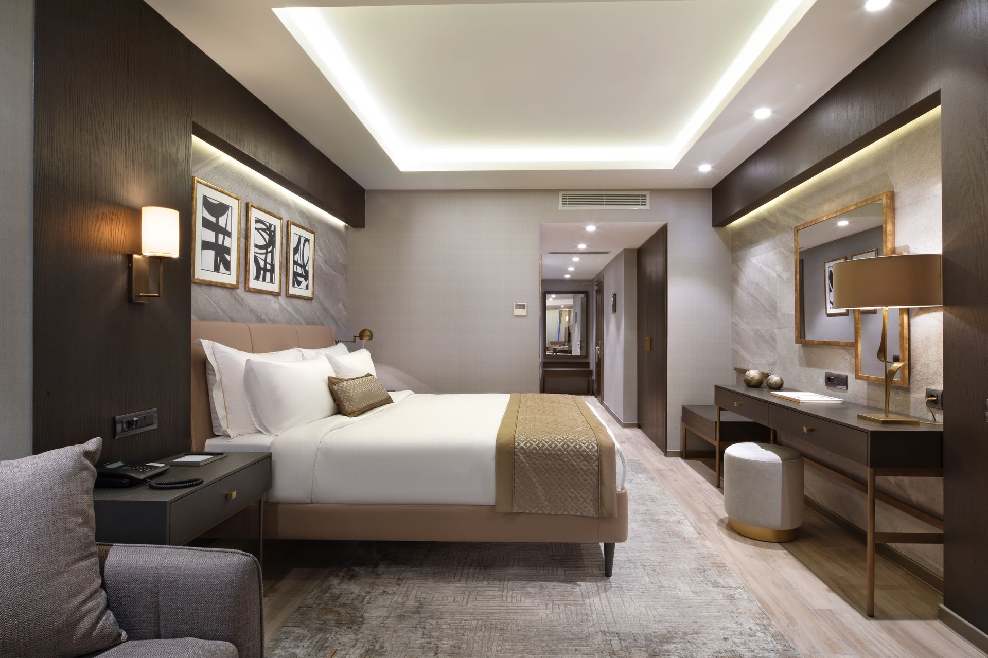 Modern hotel room with a bed, desk, mirror, and warm lighting
